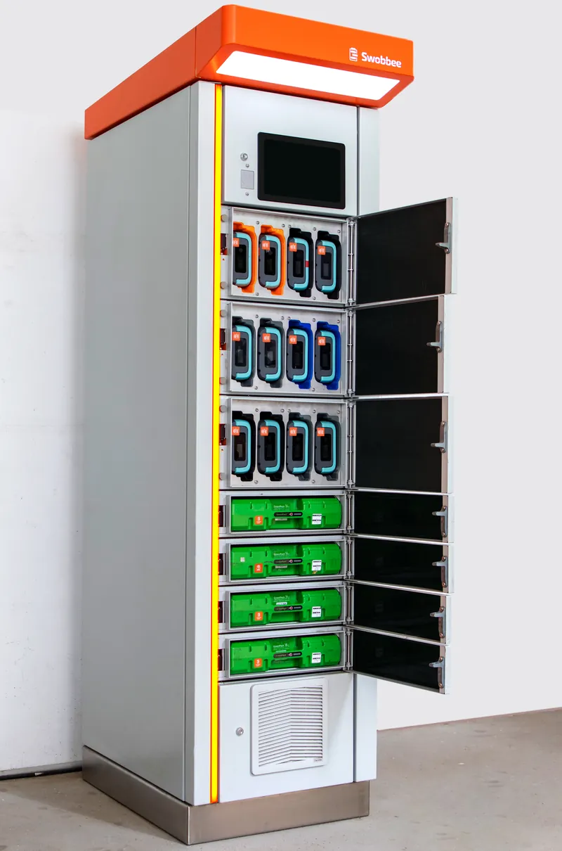 Swobbee Station mit offenen Türen: Licht oben, Display mit RFID-Leser, drei 4er-Fächer mit verschiedenen Akkutypen und vier 1er-Fächer mit GreenPack-Akkus