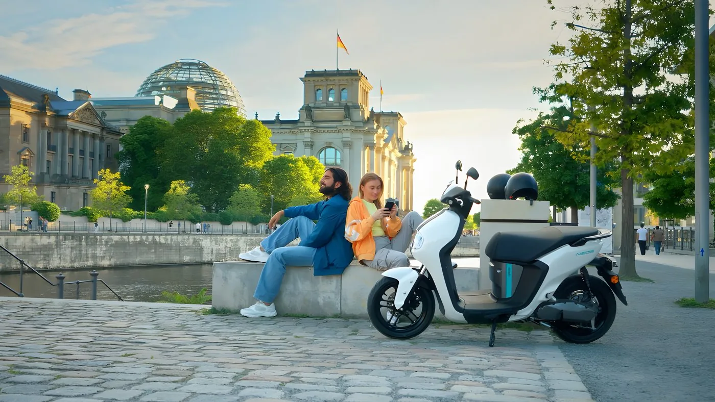 Weisser Yamaha E-Roller auf der Spreepromenade in Berlin, dahinter das Reichstagsgebäude mit der Glaskuppel
