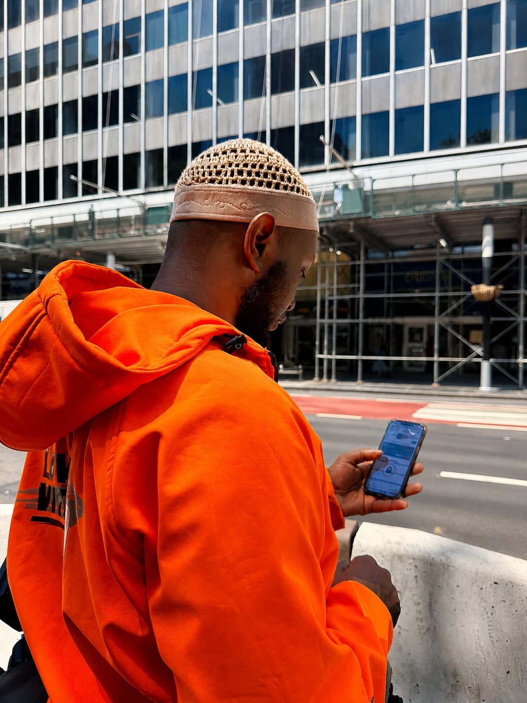 Ein Fahrer im orangen Hoodie schaut auf einer Straße in Manhattan in die Swobbee App